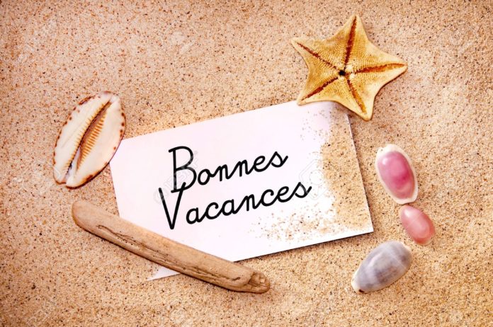 Bonnes vacances (meaning happy holiday) on a note on white beach sand, starfish and shells